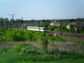 Pociąg pośród zieleni sunący po szynach w słoneczny letni dzień